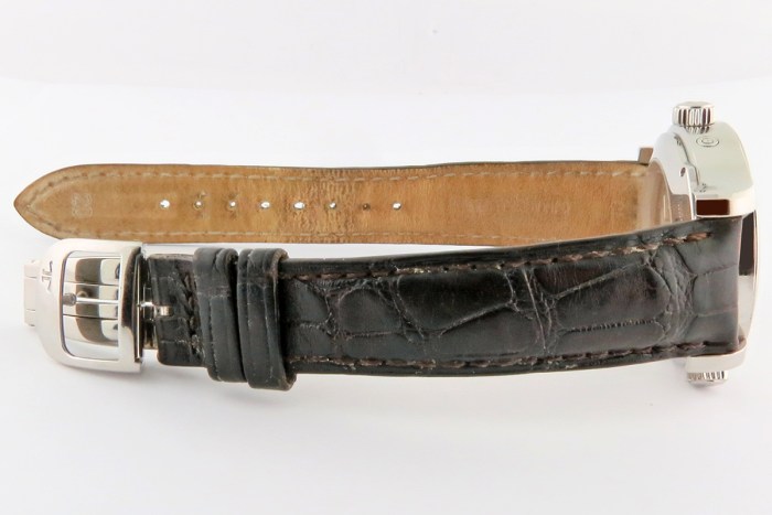 Side view of a wristwatch with a black leather strap and a silver casing, crown visible on the right.