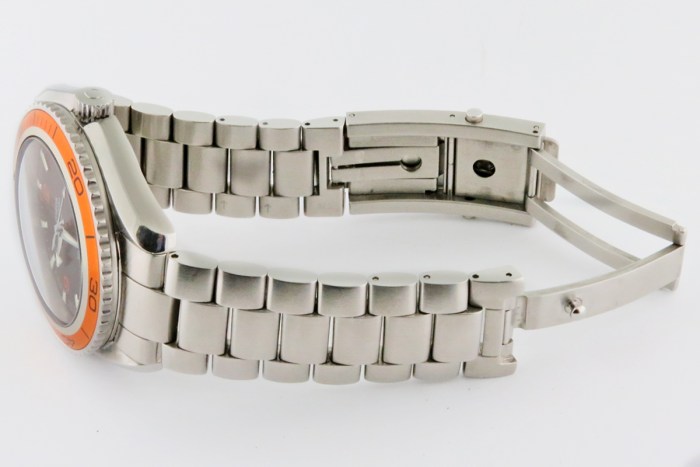 Stainless steel wristwatch with an orange bezel, shown in a side view with a metal link bracelet and deployment clasp
