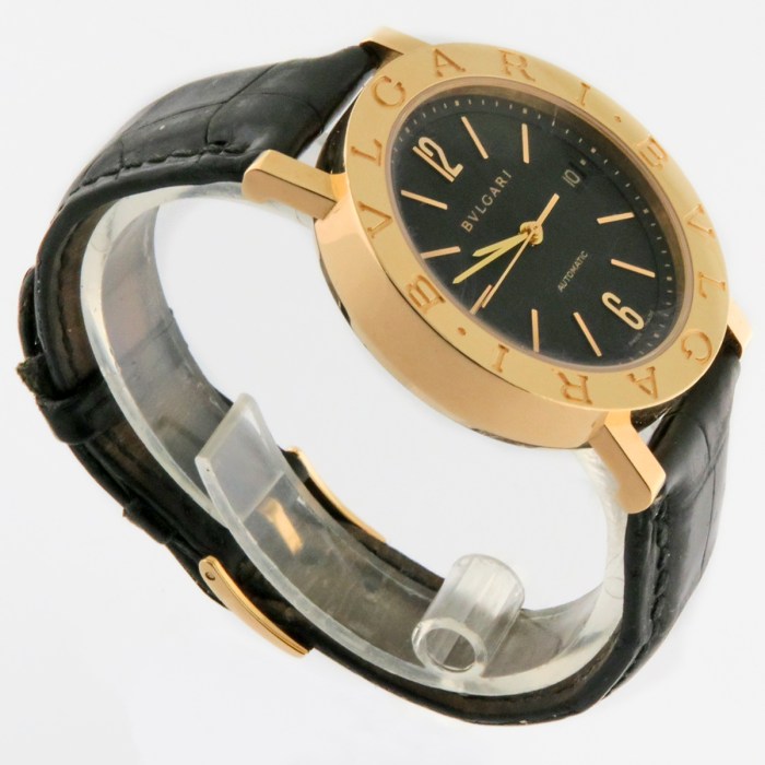 Gold BVLGARI wristwatch with black dial and black leather strap, angled to show the brand on the bezel