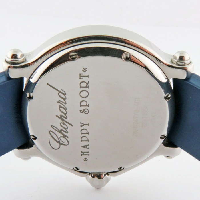 Close-up of a silver watch back with engraved 'Chopard' and 'Happy Sport' on a blue strap
