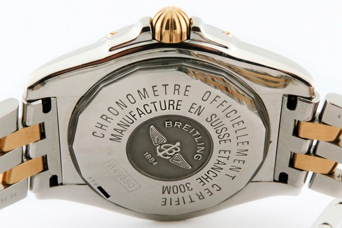 Breitling watch back with circular logo and engraved text, two-tone metal band visible