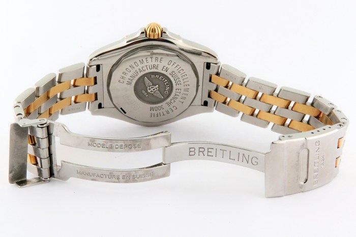 Two-tone Breitling wristwatch with a folded deployment clasp, shown from the back with engraved case and crown detail.