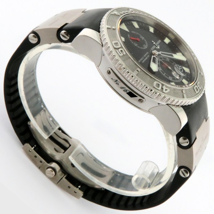 Close-up of a stainless steel dive watch with a black rubber strap, rotating bezel, and black dial with subdials and luminous markers.