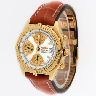 Gold Breitling chronograph watch with white dial, orange subdials, date window at 3 o'clock, and brown leather strap