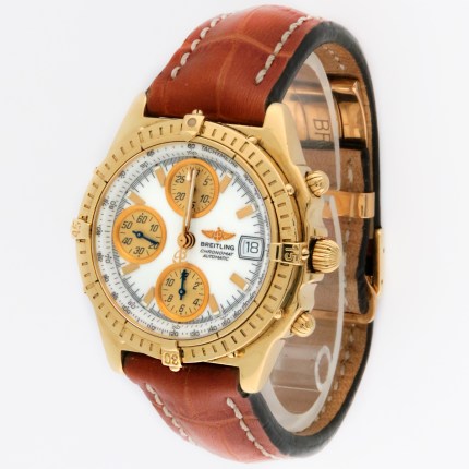 Gold Breitling chronograph watch with white dial, orange subdials, date window at 3 o'clock, and brown leather strap